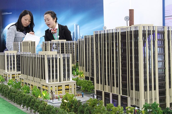 Visitors look at a model of a housing project at a real property exhibition in Beijing. (Photo provided to China Daily)