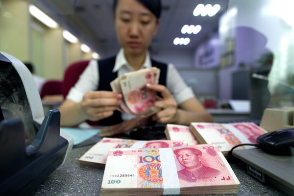 A staff member of a bank in Taiyuan, Shanxi province, counts cash at a customer-facing counter. (Photo by Zhang Yun/For China Daily)