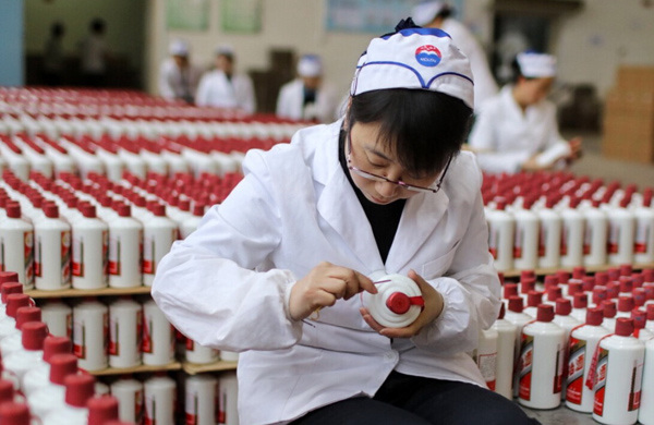 An employee of Kweichow Moutai Co Ltd puts labels onto bottles of the Chinese liquor. (Photo provided to China Daily)