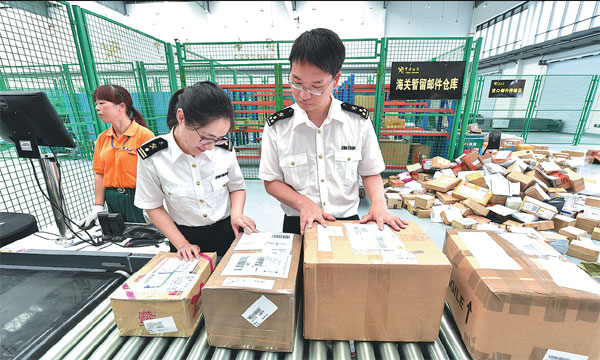 Customs officials in Yiwu, Zhejiang province, inspect e-commerce parcels from South Korea. (Photo/China Daily)