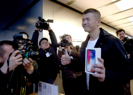 A customer flaunts his iPhone X bought from an Apple outlet in Beijing, Nov 3, 2017. The US firm posted strong revenue growth in China during the third quarter of this year. (Photo provided to China Daily)