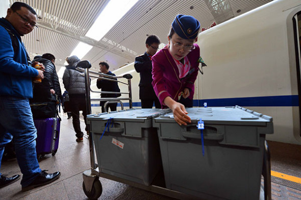 A train conductor checks cargo boxes that are being transported by bullet train in Jinan, Shandong province, during last November's Singles Day shopping spree. (Photo/Xinhua)