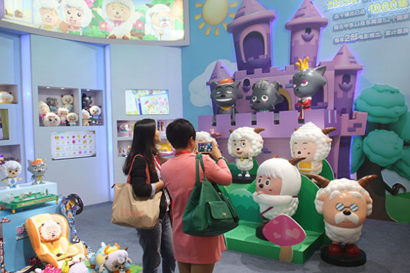 Visitors take photographs of Chinese cartoon characters, Xiyangyang (Happy Sheep) and Huitailang (Gray Wolf), created by Alpha Group at a toy exhibition in Shanghai.XING YUN/CHINA DAILY