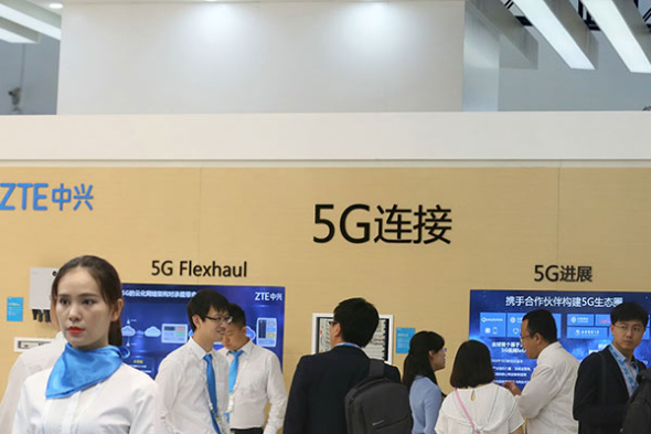 Visitors check information about 5G services at the booth of ZTE Corp at the PT/Expo China 2017 in Beijing. (A QING/CHINA DAILY)