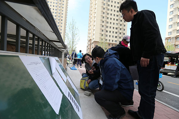 Prospective tenants check information about a public rental housing project in Beijing's Chaoyang district.(Wang Zhuangfei/China Daily)