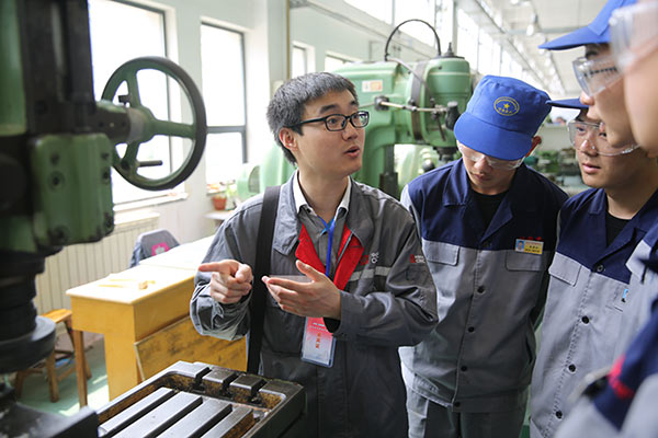 A technician of CRRC Qingdao Sifang Co Ltd, a high-speed train manufacturer, gives instructions to students at a vocational school in Shandong Province. (Photo/China Daily)