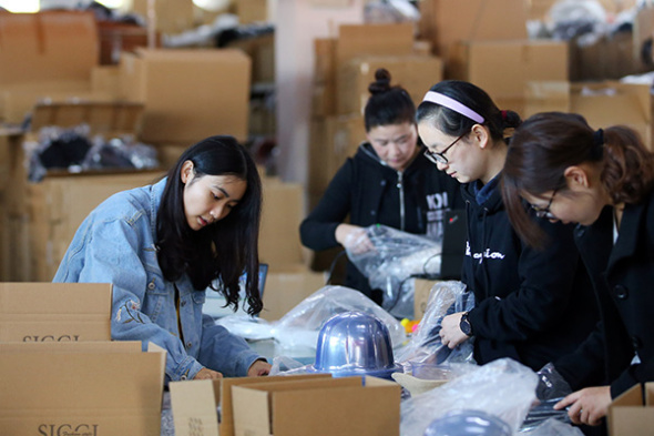 The packaging staff at the warehouse of a hat e-commerce company based in Nantong, Jiangsu province, pack products sold on Singles Day, Nov 11, 2017.（Photo/Xinhua）