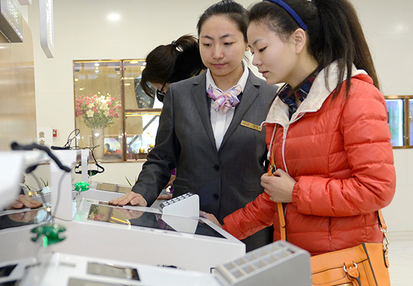 An employee (center) of the Industrial and Commercial Bank of China addresses queries from a customer on wealth management products at a Beijing branch.(Photo/Xinhua)
