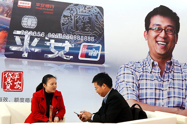 A Ping An Bank employee (left) addresses queries from a customer on credit and loan services at a financial expo held in Beijing. (Photo/for China Daily)