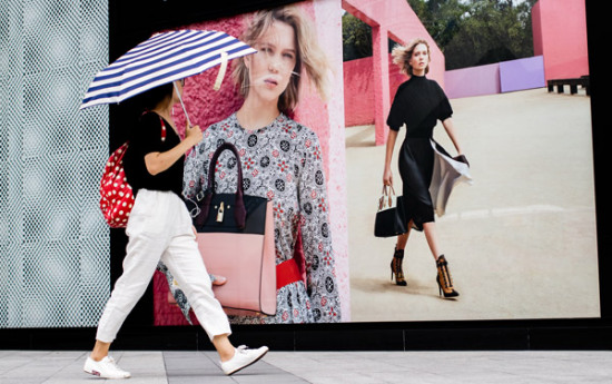 A woman walks past a Louis Vuitton advertisement in Fuzhou, capital of East China's Fujian province. (Photo by Chen Hao/For China Daily)
