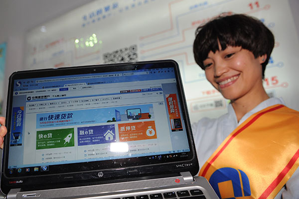 An employee of China Construction Bank showcases the bank's new online business at an exhibition in Guiyang, capital of Southwest China's Guizhou province. (Photo/Xinhua)