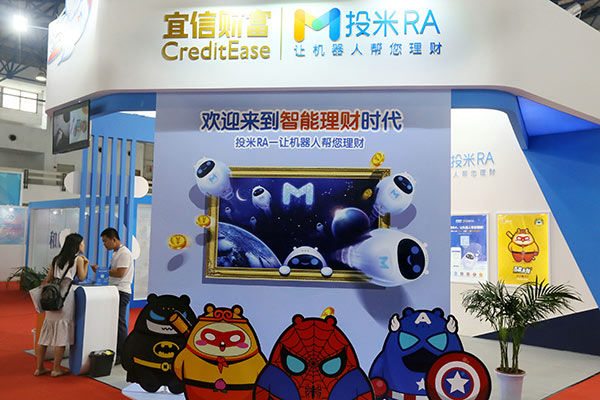 A prospective customer makes enquiries at a booth of CreditEase at a financial services exhibition in Beijing.(Photo by A Jing/China Daily)