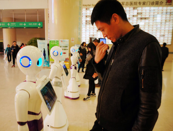 People interact with robots at the 301 Hospital in Beijing. The robots provide basic medical consultation services for people. (Photo by Fan Jiashan/for China Daily)