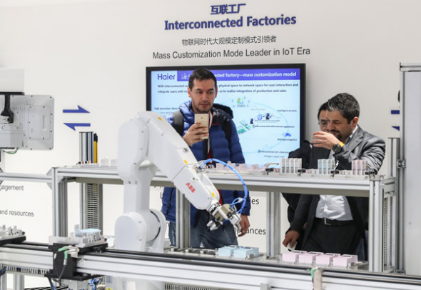 Visitors take pictures of Haier products at the Hannover Messe, a leading trade expo for industrial technology. (Photo/Xinhua)