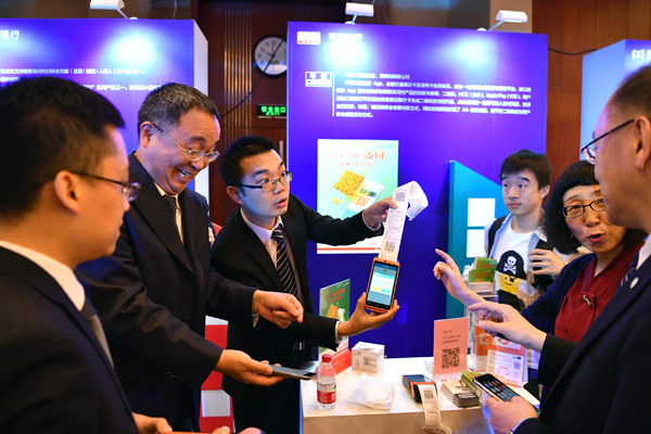 Employees introduce mobile payment application services during a promotional event in Beijing. (Photo/Xinhua)