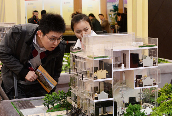 A saleswoman (right) addresses a visitor's inquiries at a housing exhibition held in Shanghai. (Photo by Lai Xinlin/For China Daily)