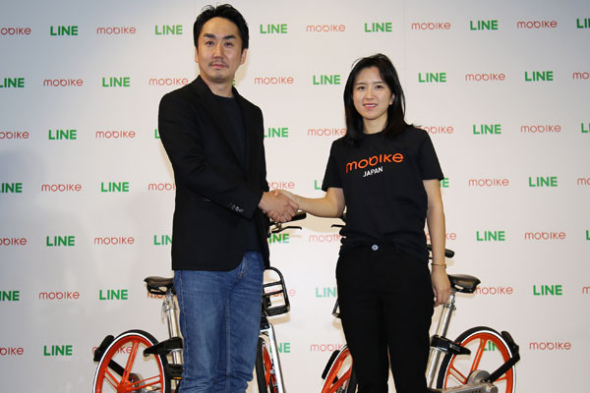 Hu Weiwei, founder and president of Mobike, right, joined hands with Takeshi Idezawa, president and CEO of LINE, at a ceremony in Japan.Photo provided to chinadaily.com.cn