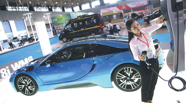 A worker at a new energy vehicle exhibition in Nanjing, Jiangsu province, shows how to charge an electric car. (Photo by Yang Bo/For China Daily)
