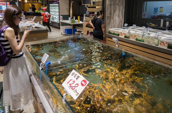 A customer chooses seafood at a supermarket of Bailian Group in Shanghai. The company is setting up a commodity trading platform targeting sales of a trillion yuan. (Photo by Wang Gang/For China Daily)