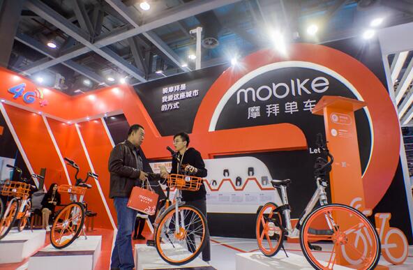 An employee (right) of Mobike addresses a visitor's inquiries at an exhibition held in Guangzhou, Guangdong province. The company ranks top in bike-sharing firms in China. (Photo by Li Zhihao/For China Daily)