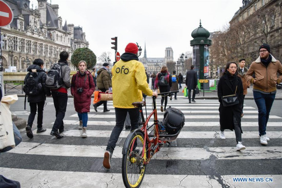 The repairer Yoann Andrieux heads across a street to maintain an Ofo bike in Paris, France, on Dec. 20, 2017. (Xinhua/Chen Yichen)