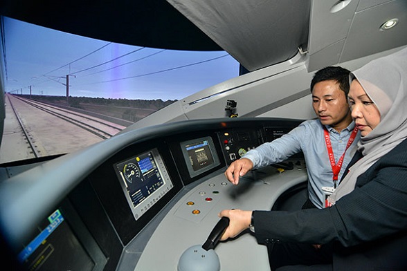 An attendant introduces the control system of a China-made high-speed train to a visitor at an exhibition in Kuala Lumpur, Malaysia. (Photo/Xinhua)