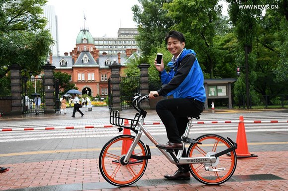 A TV reporter tries out a shared bicycle in Sapporo, Japan, on Aug. 22, 2017.(Xinhua/Hua Yi)