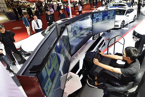 A visitor tries a self-driving system at an auto expo in Hangzhou, capital of Zhejiang Province. (Photo by Li Zhong/for China Daily)