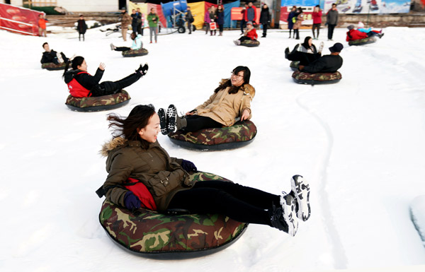 People participate in snow-related amusement activities at Beijing's Yuyuantan Park during the New Year holiday. (Photo by LIU PING/FOR CHINA DAILY)