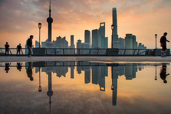 Skyscrapers are reflected in a puddle of water in the early morning at the Bund in Shanghai, Oct 20, 2015.(Photo/Xinhua)