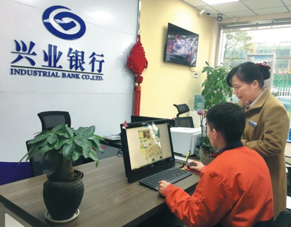 A worker (left) at Geely Auto Group's Chunxiao Manufacturing Plant in Ningbo, Zhejiang province, applies for a consumer loan using online services of Industrial Bank. (Photo by Chen Jia / China Daily)