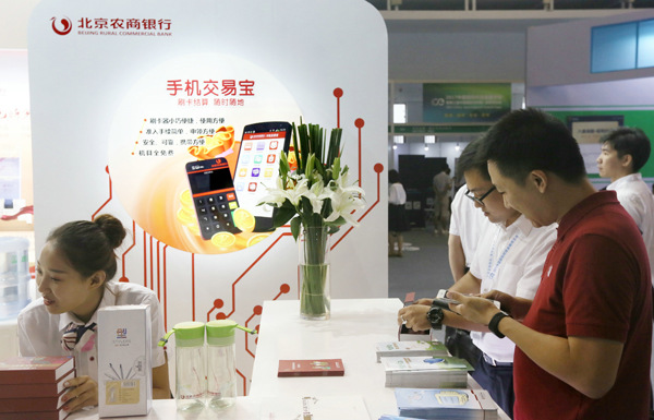 A staff member of Beijing Rural Commercial Bank introduces the company's mobile app to a client at the 2nd China (Beijing) International Internet Era Exposition. (Photo provided to China Daily)