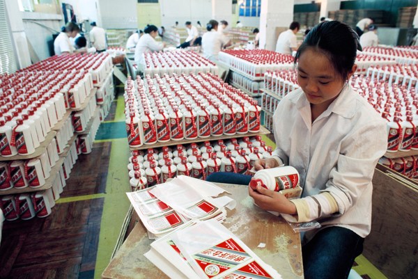 An employee pastes labels onto Moutai bottles at a facility in Huairen, Guizhou province. The company is planning to increase supplies before the upcoming Spring Festival. (Photo provided to China Daily)