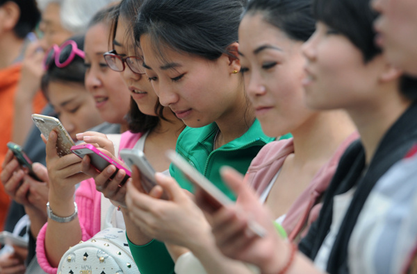 A group of women use their mobile phones outside a department store in Taiyuan, capital of Shanxi province. (Photo by Liu Jiang/For China Daily)