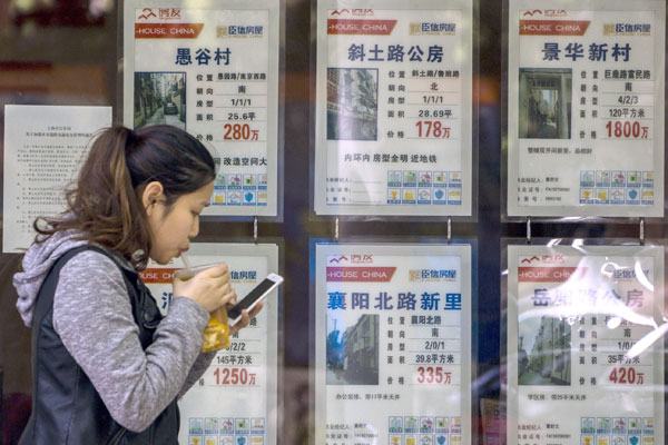 A pedestrian walks past a property agency in Shanghai. (Photo by Zhang Peng/For China Daily)