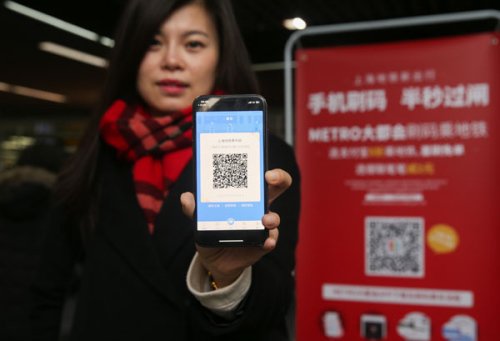 A passenger shows her QR code to enter the metro station at the People's Square in Shanghai. (Photo/Xinhua)