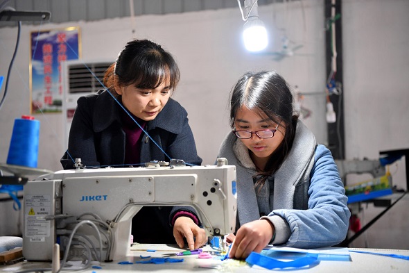 Workers sew a shopping bag in Lyu Xiaofang's factory in Shangshui county, Henan province. (Photo/Xinhua)