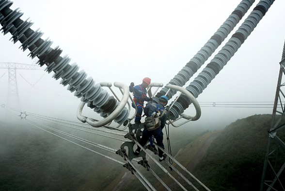 Two technicians from China Southern Power Grid inspect the Guizhou section of the 800kV Northwestern Yunnan-Guangdong UHV DC power transmission project. (Photo/Xinhua)