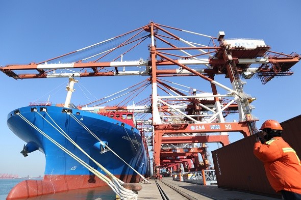 A port employee directs the cargo loading of a COSCO ship in Qingdao, Shandong province. (Photo by Zhang Jingang/For China Daily)