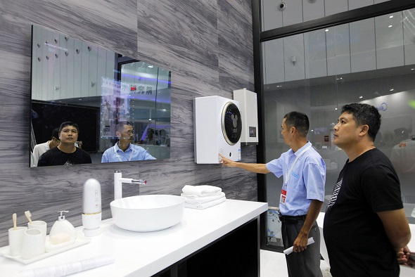 Visitors look at a smart mirror, which can monitor people's skin conditions, at the smart home products center of leading Chinese home appliance maker Midea Group in Foshan, South China's Guangdong province. (Photo/China Daily)