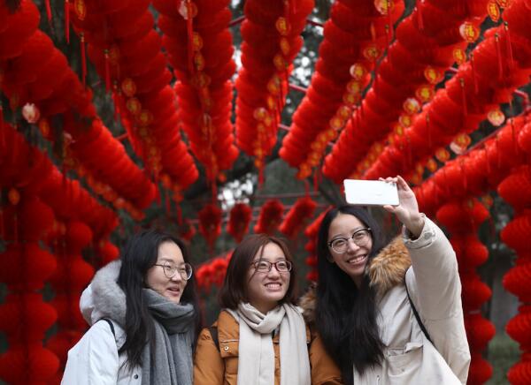 Tourists take a selfie with a smartphone in a corridor decorated with red lanterns in Beijing's Ditan Park over the weekend. (Photo/Xinhua)