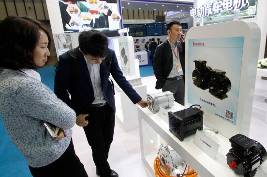 Visitors examine electric motors used in e-vehicles at an industry expo held in Nanjing, capital of Jiangsu province. (Photo by Dong Quanlin/For China Daily)