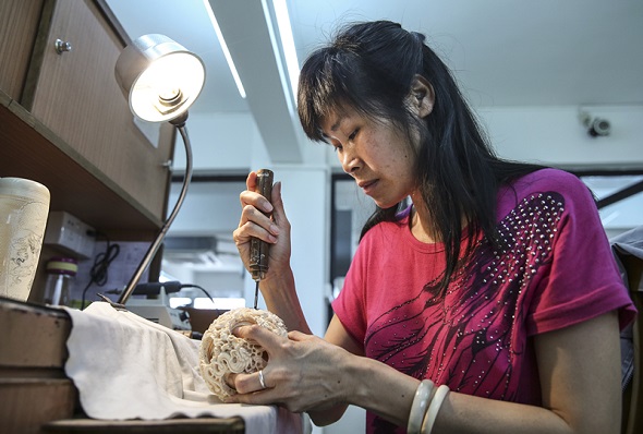 Qiu Yuying, an ivory carver from Guangdong province, displays her skills by making an ivory ball in 2017. (Zou Hong/China Daily)