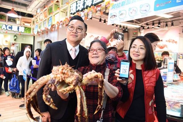 A woman shows the Alaska king crab she purchased with just one HK dollar (13 U.S. cents) during a street market promotion event hosted by Alipay in Hong Kong on Dec 12, 2017. (Photo/Xinhua)