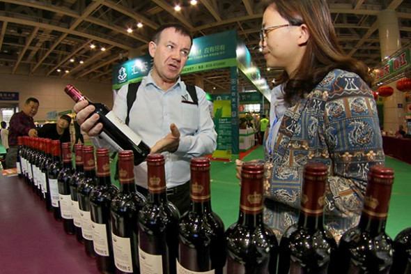 A foreign merchant presents wines to visitors during the 10th Yantai International Wine Exposition in Yantai, East China's Shandong province.(Photo by Tang Ke/for China Daily)