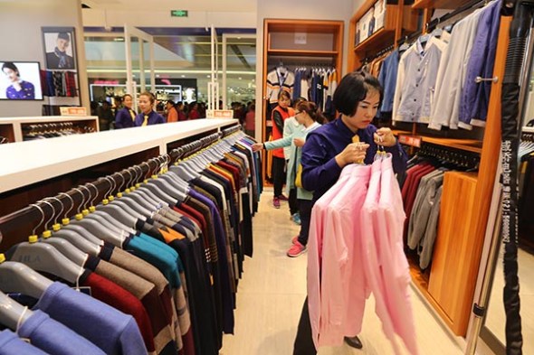 A saleswoman puts shirts on a clothes rack at a Heilan outlet in San Menxia city, Henan province.Photo by Sun Meng/for China Daily