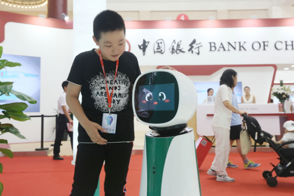 A child interacts with Bank of China's robot receptionist during the 25th China International Financial Exhibition in Beijing. (Photo by A Jing/For China Daily)