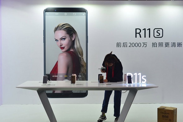 A customer browses Oppo smartphones at a promotion campaign of the company in Beijing in November 2017. (Photo by Fan Jiashan/For China Daily)