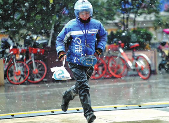 A deliveryman rushes to offer food to a customer amid snowfall in Jinan, Shandong province, East China. Photo by Yu Ning/For China Daily