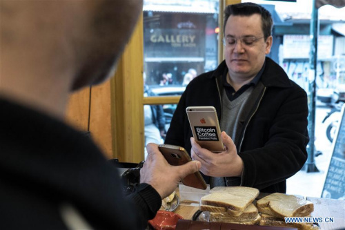 A customer uses his mobile phone to pay with bitcoin at a coffee shop in the center of Athens, Greece, Feb. 25, 2018. (Xinhua/Lefteris Partsalis)